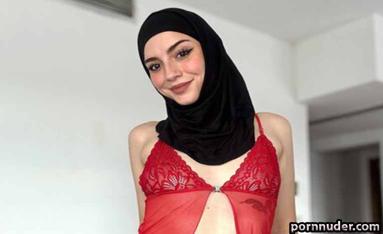 Shemale Sex Doll: A Perfect Hotel Companion That Will Never Embarrass You Woman in a red lace lingerie top and black hijab, smiling at the camera indoors.